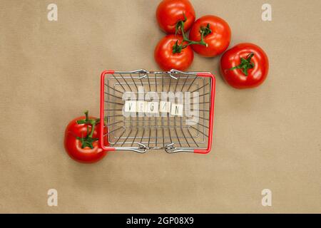 Vegan geschrieben auf Holzwürfeln, umgeben von Gemüse in Einkaufskorb Draufsicht mit Bastelpapier Hintergrund, Vegan, gesundes Essen, Vegetarische Konce Stockfoto