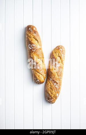 Zwei knusprige frische Baguettes auf einem weißen Tisch. Draufsicht. Stockfoto