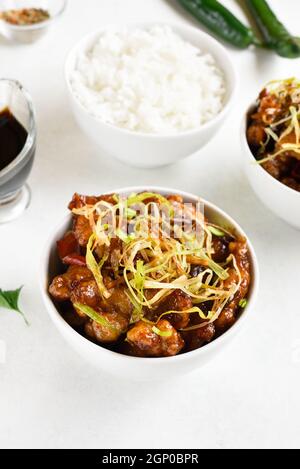 Würziges, gebratenes Huhn (Kkanpunggi) mit Knoblauch. Asiatisches Huhn in süßer und saurer Sauce in Schüssel auf weißem Hintergrund. Stockfoto