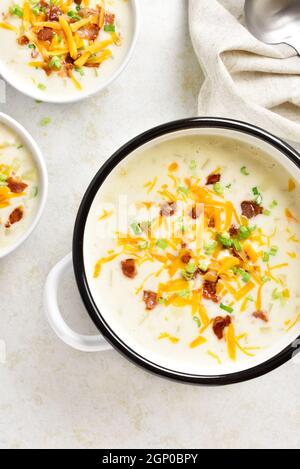 Cremige Kartoffelsuppe mit Speck und Cheddar Käse in Schüssel auf hellem Stein Hintergrund. Gesunde Ernährung Gericht zum Abendessen. Ansicht von oben, flach Stockfoto