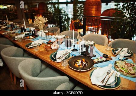 Wunderschön gedeckte Tische mit Essen, Gläsern und Geräten im Restaurant. Stockfoto