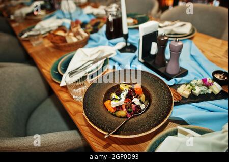 Wunderschön gedeckte Tische mit Essen, Gläsern und Geräten im Restaurant. Stockfoto