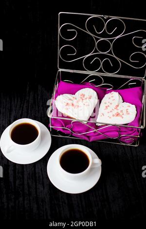 Valentinstag: zwei Tassen Kaffee und Gebäck in der Form von Herzen. Stockfoto