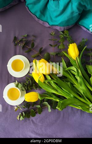 Gelbe Tulpen und zwei Tassen Tee im Bett, am Morgen. valentinskarte Stockfoto