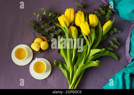 Gelbe Tulpen und zwei Tassen Tee im Bett Stockfoto