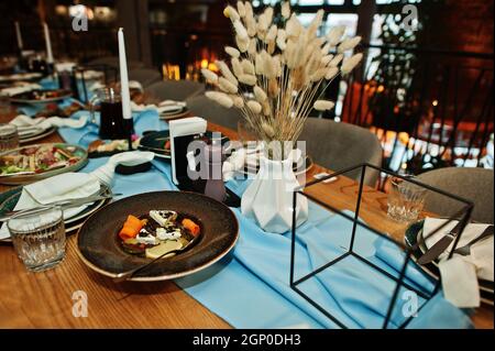 Wunderschön gedeckte Tische mit Essen, Gläsern und Geräten im Restaurant. Stockfoto