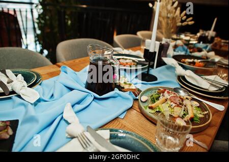 Wunderschön gedeckte Tische mit Essen, Gläsern und Geräten im Restaurant. Stockfoto