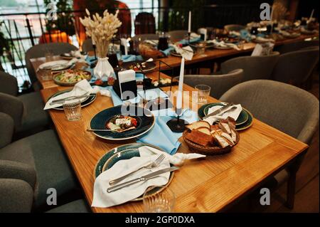 Wunderschön gedeckte Tische mit Essen, Gläsern und Geräten im Restaurant. Stockfoto