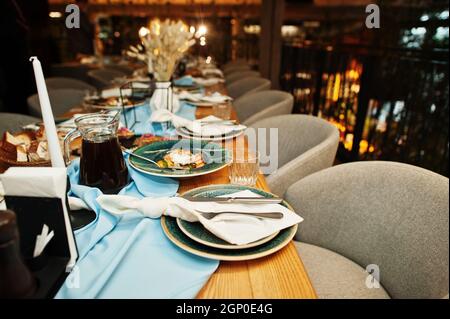 Wunderschön gedeckte Tische mit Essen, Gläsern und Geräten im Restaurant. Stockfoto