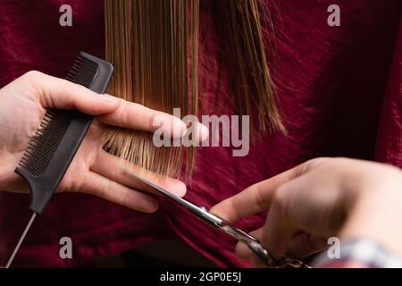 Nahaufnahme von Friseur Schneiden blonde Frauen trockenes Haar endet zu Hause oder im Salon. Stockfoto