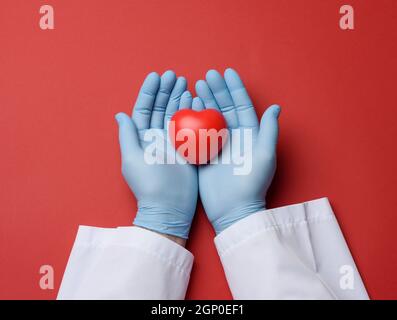 Zwei Hände in blauen Latex-Handschuhen mit rotem Herz, Spendenkonzept, Draufsicht Stockfoto