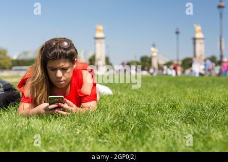 Glückliche Frau in Paris überprüfen ihr Smartphone News Stockfoto