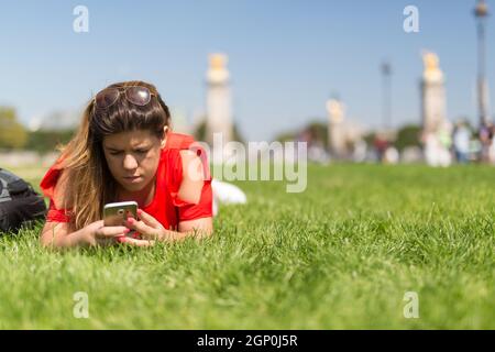 Glückliche Frau in Paris überprüfen ihr Smartphone News Stockfoto