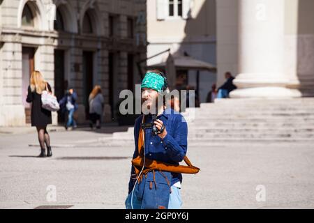 Triest, Italien - Mai, 31: Hipster, der am 31. Mai 2021 mit einer Videokamera mit Kopfhörern in der Stadt mit Bandana unterwegs ist Stockfoto