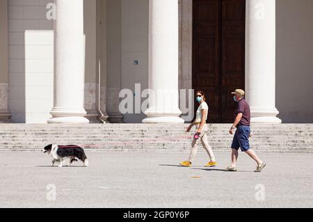 Triest, Italien - Mai, 31: Ein Paar mit Gesichtsmaske allein auf dem Platz geht Hund während der Pandemie am 31. Mai 2021 Stockfoto