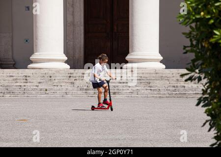 Triest, Italien - Mai, 31: Jugendlich Kind auf einem Roller auf dem Stadtplatz am 31. Mai 2021 Stockfoto