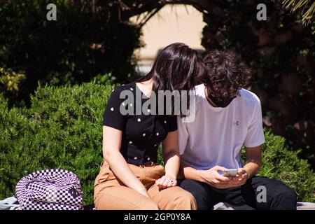 Triest, Italien - Mai, 31: Ehepaar mit Intimität sitzt auf einer Bank mit Smartphones am 31. Mai 2021 Stockfoto