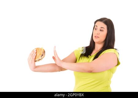 Schöne große Frau, die versucht, zu einem appetitlichen Hamburger widerstehen können, die ihre Ernährung töten würde Stockfoto