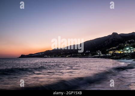 Kleine Wellen und Küstenlinie bei Sonnenuntergang in Keratokampos, Kreta Stockfoto