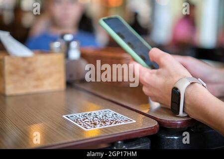 Nahaufnahme der Gäste, die eine Mahlzeit im Restaurant bestellen, während der QR-Code mit dem Mobiltelefon gescannt wird, um ein Online-Menü zu erhalten. Stockfoto