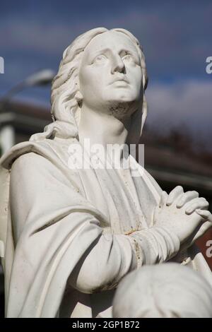 Schöner Gesichtsausdruck auf Maria Magdalena, ihre Hände in dieser alten Friedhofsstatue gebettet. Stockfoto