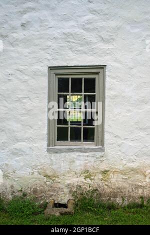 Vertikales Bild einer weißgetünchten Steinfassade eines kolonialen amerikanischen Hauses mit einem blauen 12-Fenster, das durch ein Fenster auf dem anderen sid blickt Stockfoto