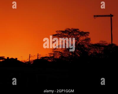 Städtische Silhouetten unter einem orangefarbenen Himmel während der Dämmerung. Stockfoto