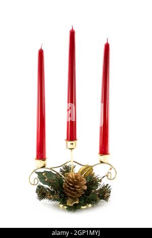 Drei brennende rote Kerzen in Weihnachten Motto Kiefer verziert Messing Kerzenhalter Tischdekoration auf weißem Hintergrund isoliert Stockfoto