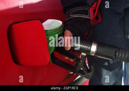 Befüllen Sie das Auto mit einer Benzinpistole an einer Tankstelle mit männlicher Hand. Rohölpreise und Gaspreise. Der teuerste Kraftstoff der Welt. Stockfoto