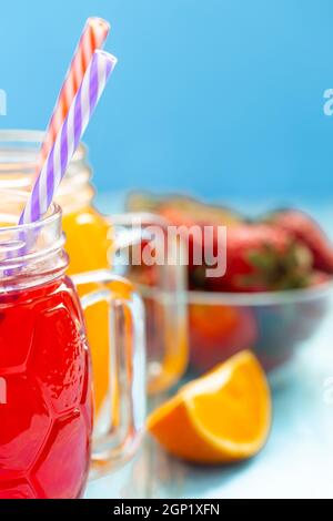 Zwei Tassen mit Orangensaft und Erdbeeren auf blauem Hintergrund Stockfoto