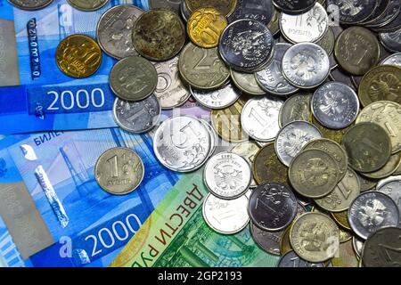 Russische Banknoten und Münzen. Eine Handvoll Münzen auf Neue Russische Banknoten im Wert von 2000 und 200 Rubel Stockfoto