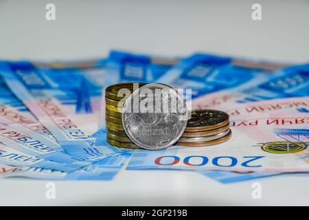 Russische Banknoten und Münzen. Eine Handvoll Münzen auf Neue Russische Banknoten im Wert von 2000 und 200 Rubel Stockfoto