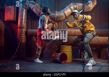 Zwei ernsthafte Rapper, Breakdance, die im Studio mit cooler Underground-Dekoration auftreten. Hip-Hop-Darsteller, trendige Rap-Sänger, Breakdancer Stockfoto
