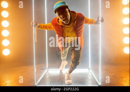 Stilvoller Rapper auf der Bühne mit beleuchtetem Würfel. Hip-Hop-Performer, Rap-Sänger, Break-Dance-Performer, Entertainment-Lifestyle Stockfoto