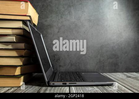 Ein offener Laptop auf dem Tisch in der Nähe des Bücherstapels. Stockfoto