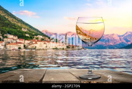 Wineglass auf altem Holztisch auf einem Hintergrund von Perast, Montenegro Stockfoto