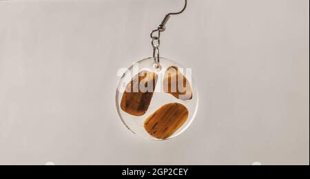 Handgemachte Anhänger Ohrring aus Kunstharz transparent mit Farbe kleinen Steinen Stockfoto