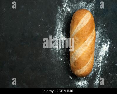 Britisches Weißblüher oder europäisches Baton-Brot auf schwarzem Hintergrund. Draufsicht oder flaches Lay. Platz für Text oder Design kopieren Stockfoto