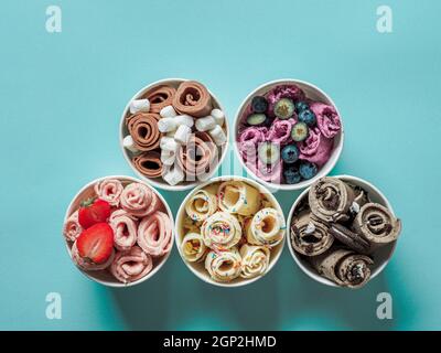 Eiscremes in Kegelbecher auf blauem Grund gerollt. Verschiedene Eisrollen, Draufsicht oder flache Lage. Thailändisches Eiscreme Stockfoto