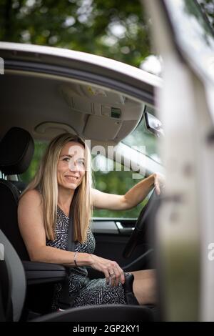 Hübsche Frau im mittleren Alter am Steuer von ihr Auto pendeln zur Arbeit Stockfoto