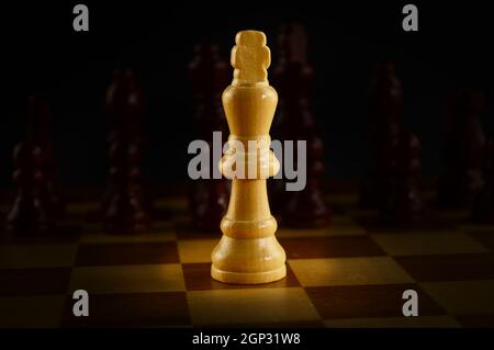 Ein Schachspielbrett mit einem beleuchteten König gegen die gegnerische Armee. Stockfoto