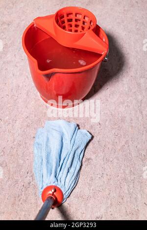 Standpunkt des Mops reinigt Linoleum Boden in der Nähe rot Eimer mit Wasser zu Hause Stockfoto