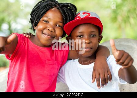 Nahaufnahme des Außenportraits von afrikanischen Brüdern und Schwestern, die Daumen hoch machen. Stockfoto