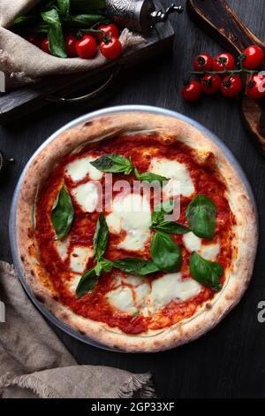 Traditionelle italienische Pizza Margarita. Basilikumblätter und Tomatensauce. Metallplatte zum Servieren von Speisen. Vertikales Foto. Draufsicht. Stockfoto