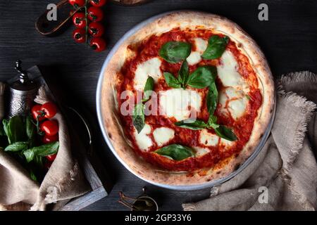 Traditionelle italienische Pizza Margarita. Basilikumblätter und Tomatensauce. Metallplatte zum Servieren von Speisen. Vertikales Foto. Draufsicht. Stockfoto