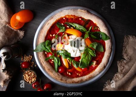 Pizza mit Burrata-Käse und Pinienkernen. Italienische Pizza. Metallplatte zum Servieren. Grüne Basilikumblätter. Draufsicht. Stockfoto