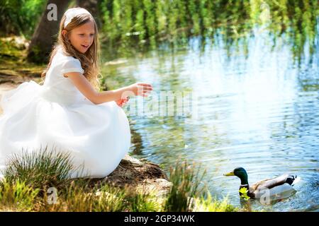 Porträt von niedlichen jungen Mädchen Fütterung einer Ente am Flussufer. Stockfoto