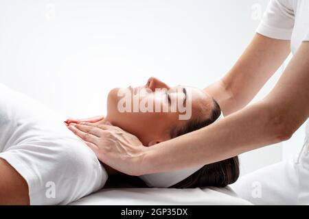 Porträt der jungen Frau an Reiki-Sitzung hautnah. Therapeut berührt Hals Wit Frauenhand. Stockfoto