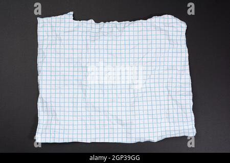 Textur aus zerknittertem weißem Papier in einem Käfig, blaue Linien, abgerissene Kanten auf schwarzem Hintergrund Stockfoto