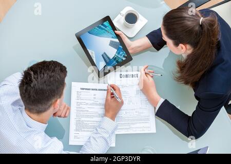 Junges Unternehmen paar Mietvertrag diskutieren. Frau, Mann Bürogebäude auf digital-Tablette am Tisch. Stockfoto